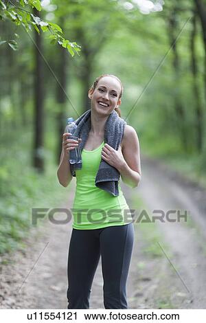 Stock Image - Portrait of woman jogging in forest. Fotosearch