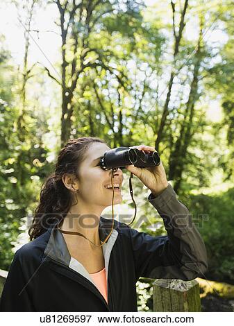 Stock Photo - Portrait of woman looking at view with binoculars. Fotosearch