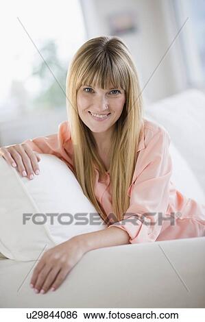 Stock Photograph - Portrait of woman sitting on sofa. Fotosearch
