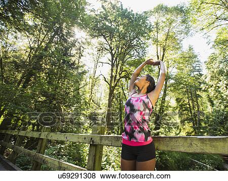 Stock Photo - Portrait of young woman stretching on footbridge. Fotosearch