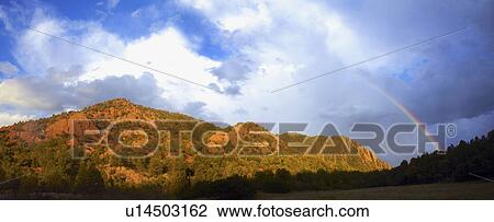 Stock Image - Rainbow over mountain range. Fotosearch