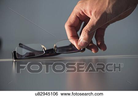 Stock Photograph - Studio shot of hand reaching for eyeglasses. Fotosearch