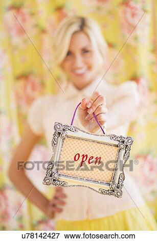 Stock Photo - Teen (16-17) girl holding open sign. Fotosearch