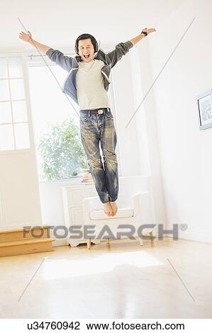 Stock Image - Teenage boy (16-17) dancing in living room. Fotosearch