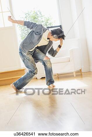 Stock Image - Teenage boy (16-17) dancing in living room. Fotosearch