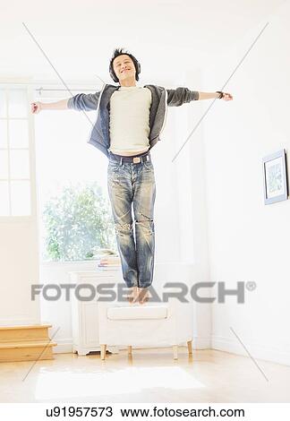 Stock Image - Teenage boy (16-17) dancing in living room. Fotosearch