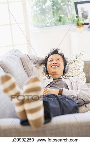 Teenage boy (16-17) lying on sofa and listening to music View Large Photo Image Stock Image - Teenage boy (16-17) lying on sofa and listening to music. Fotosearch