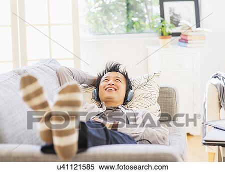 Teenage boy (16-17) lying on sofa and listening to music View Large Photo Image Stock Photography - Teenage boy (16-17) lying on sofa and listening to music. Fotosearch