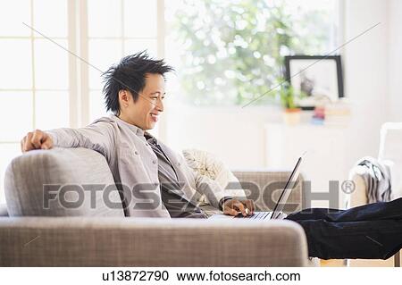 Teenage boy (16-17) sitting on sofa and using laptop View Large Photo Image Stock Image - Teenage boy (16-17) sitting on sofa and using laptop. Fotosearch