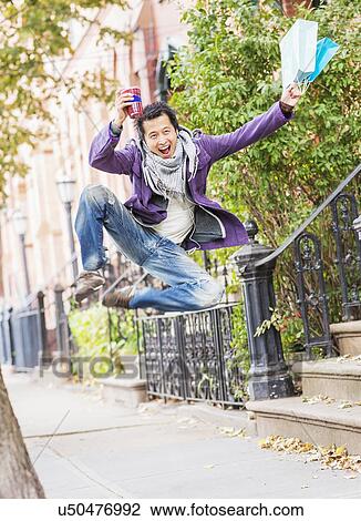 Stock Image - Teenage boy (16-17) with shopping bags drinking smoothie. Fotosearch