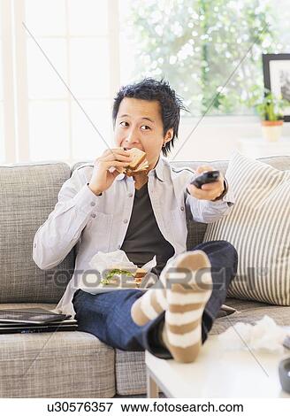 Teenage boy(16-17) eating sandwich and watching tv View Large Photo Image Stock Photo - Teenage boy(16-17) eating sandwich and watching tv. Fotosearch