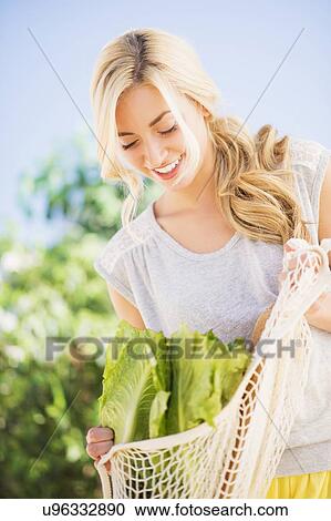 Stock Image - Teenage girl (16-17) with lettuce and bread. Fotosearch