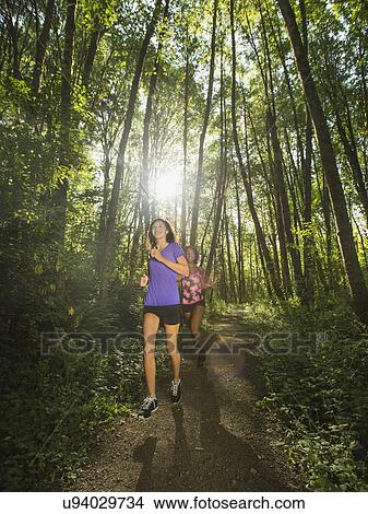 Picture - Two young women jogging in forest. Fotosearch