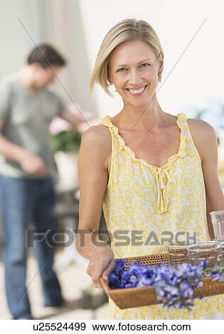 Stock Photo - Woman carrying tray with crockery and flowers. Fotosearch