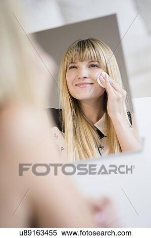 Stock Photography - Woman cleansing face with cotton pad. Fotosearch