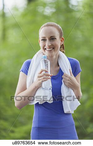 Woman drinking water during jogging in forest View Large Photo Image Picture - Woman drinking water during jogging in forest. Fotosearch