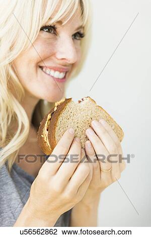 Stock Image - Woman eating sandwich with peanut butter. Fotosearch