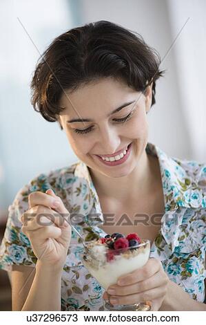 Stock Image - Woman eating yogurt with fruits. Fotosearch