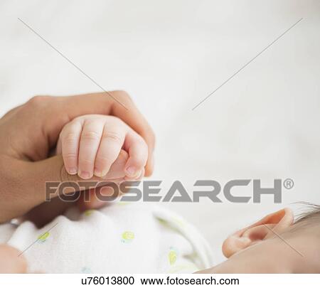 Stock Image - Woman holding baby's (2-5 months) hand. Fotosearch