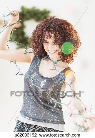 Stock Image - Woman holding christmas lights. Fotosearch