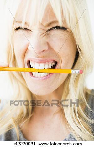 Woman holding pencil in her mouth View Large Photo Image Stock Image - Woman holding pencil in her mouth. Fotosearch