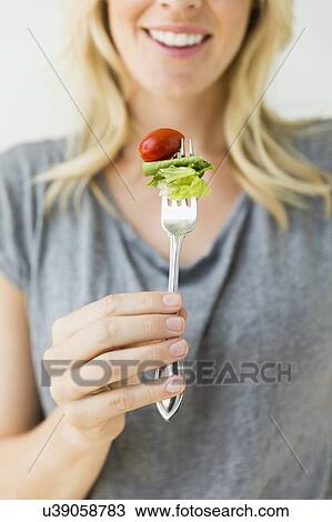 Stock Image - Woman holding salad on fork. Fotosearch