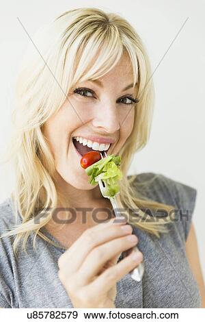 Stock Photo - Woman holding salad on fork. Fotosearch