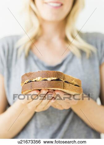 Stock Photograph - Woman holding sandwich with peanut butter. Fotosearch