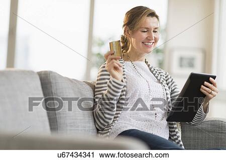 Stock Image - Woman holding tablet pc and credit card. Fotosearch