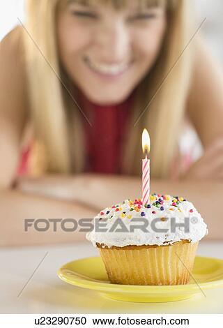 Woman looking at birthday cupcake View Large Photo Image Stock Image - Woman looking at birthday cupcake. Fotosearch