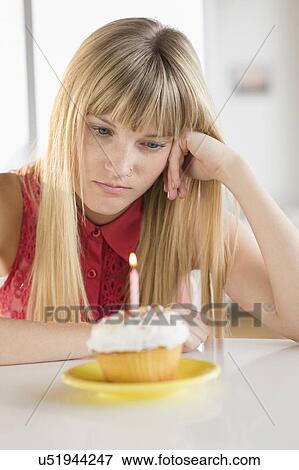 Woman looking at birthday cupcake View Large Photo Image Stock Photo - Woman looking at birthday cupcake. Fotosearch