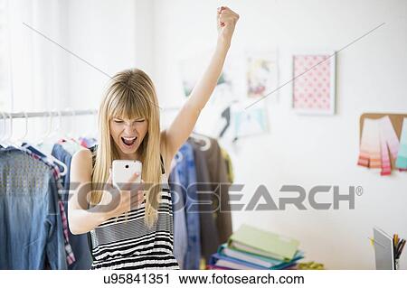 Woman looking at cell phone and cheering View Large Photo Image Stock Image - Woman looking at cell phone and cheering. Fotosearch