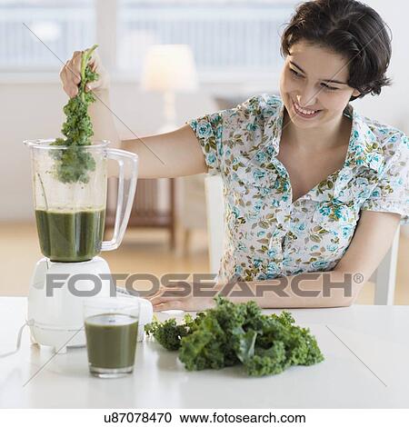 Stock Image - Woman preparing healthy drink with kale. Fotosearch