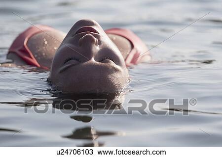 Stock Image - Woman relaxing in lake. Fotosearch