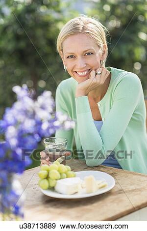 Woman sitting at table outdoors View Large Photo Image Stock Photo - Woman sitting at table outdoors. Fotosearch