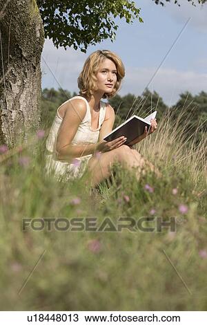 Woman sitting on grass and reading book View Large Photo Image Stock Image - Woman sitting on grass and reading book. Fotosearch
