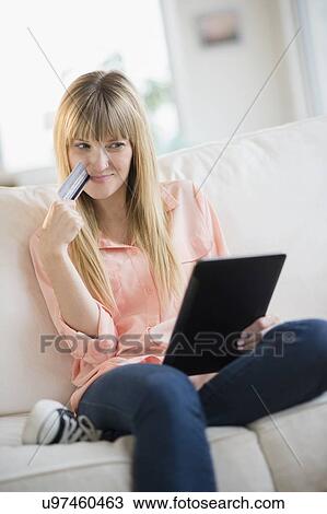 Woman sitting on sofa holding credit card and tablet pc View Large Photo Image Stock Image - Woman sitting on sofa holding credit card and tablet pc. Fotosearch