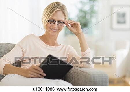Woman sitting on sofa using tablet pc View Large Photo Image Stock Image - Woman sitting on sofa using tablet pc. Fotosearch