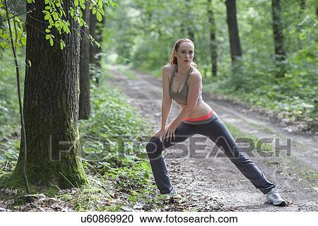 Stock Image - Woman stretching in forest. Fotosearch