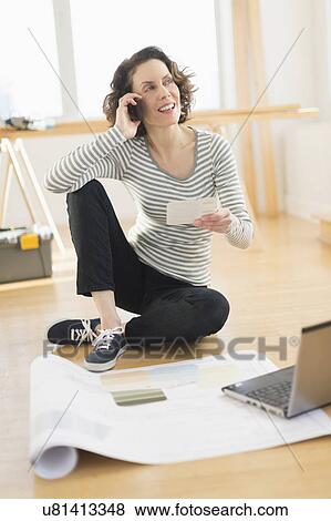 Stock Photo - Woman talking on cell phone and using laptop. Fotosearch
