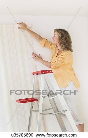 Woman trying out new wallpaper at home View Large Photo Image Stock Image - Woman trying out new wallpaper at home. Fotosearch