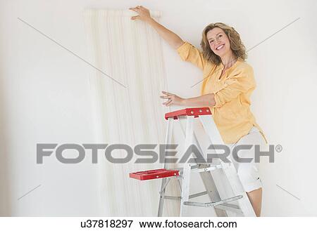 Woman trying out new wallpaper at home View Large Photo Image Stock Photo - Woman trying out new wallpaper at home. Fotosearch