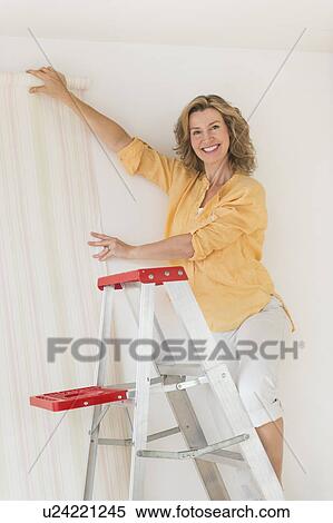 Woman trying out new wallpaper at home View Large Photo Image Stock Photography - Woman trying out new wallpaper at home. Fotosearch