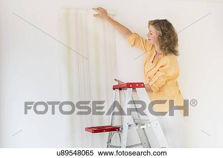 Woman trying out new wallpaper at home View Large Photo Image Stock Photography - Woman trying out new wallpaper at home. Fotosearch