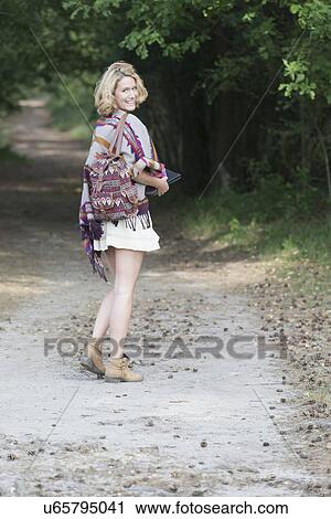 Stock Image - Woman walking dirt road. Fotosearch