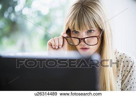 Woman wearing glasses working on computer View Large Photo Image Stock Photo - Woman wearing glasses working on computer. Fotosearch