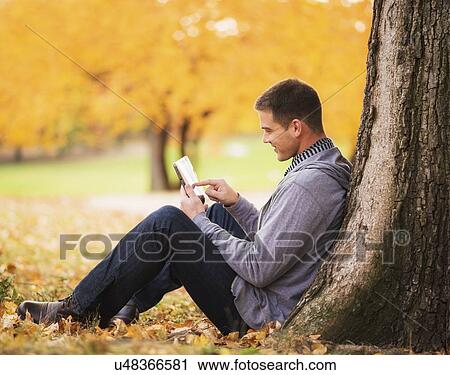 Young man using digital tablet in Central Park View Large Photo Image Stock Image - Young man using digital tablet in Central Park. Fotosearch