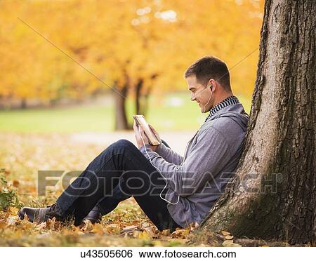 Stock Photograph - Young man using digital tablet in Central Park. Fotosearch