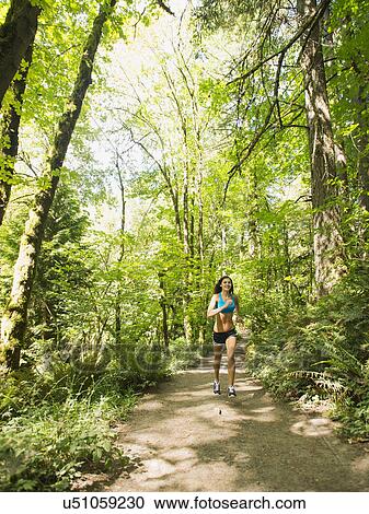 Young woman jogging in forest View Large Photo Image Stock Image - Young woman jogging in forest. Fotosearch