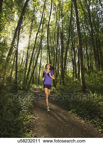 Young woman jogging in forest View Large Photo Image Stock Image - Young woman jogging in forest. Fotosearch